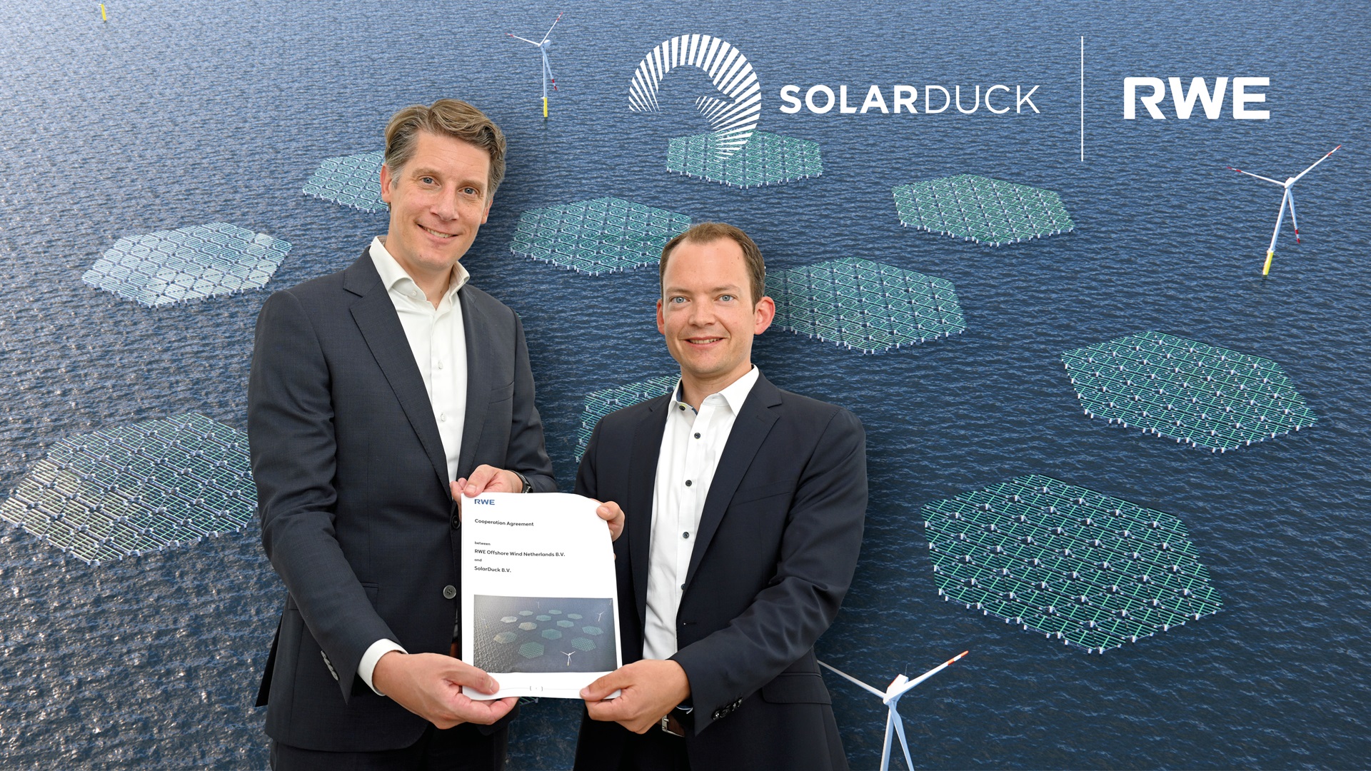Zwei Fachleute halten eine Kooperationsvereinbarung mit Solarpanelen und Windturbinen im Hintergrund.