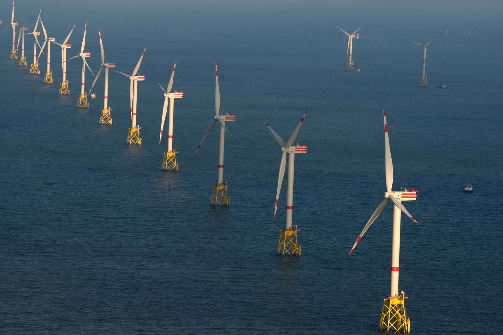 A row of wind turbines located in the sea, visible in a clear weather image.