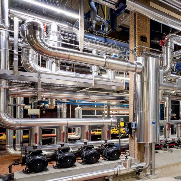Eine industrielle Rohrleitung mit glänzenden, silbernen Rohren und mehreren Motoren in einer funktionalen Umgebung.