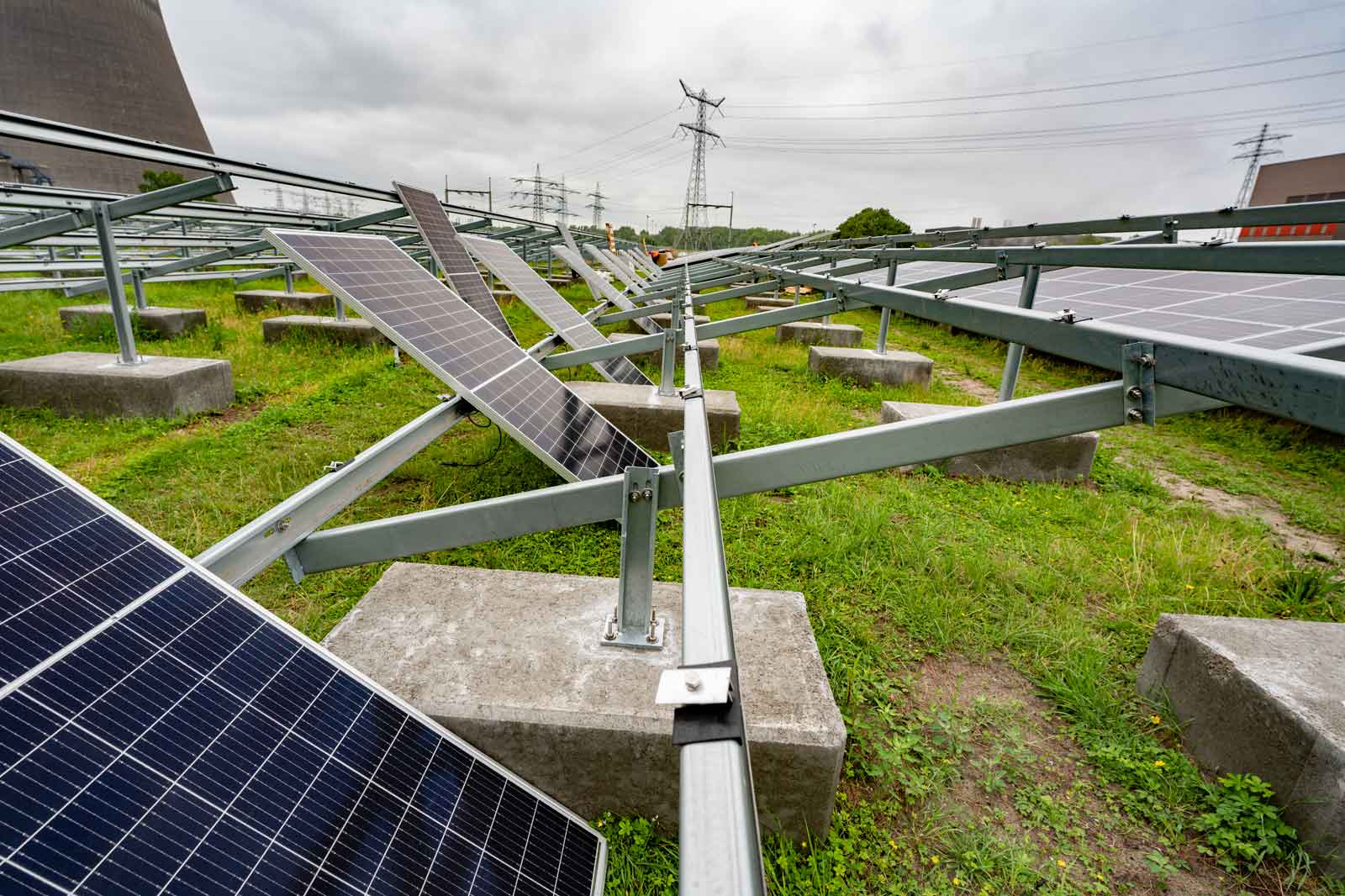 Ein Solarpanelfeld mit mehreren aufgestellten Solarmodulen und Betonfundamenten auf grünem Grasboden.
