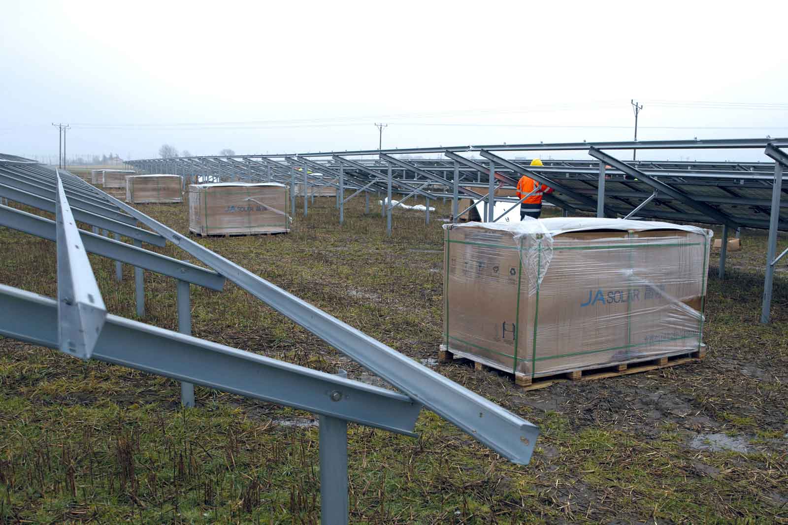 Ein Lagerbereich mit Paletten von verpackten Materialien unter solarpanel Rahmen an einem bewölkten Tag.