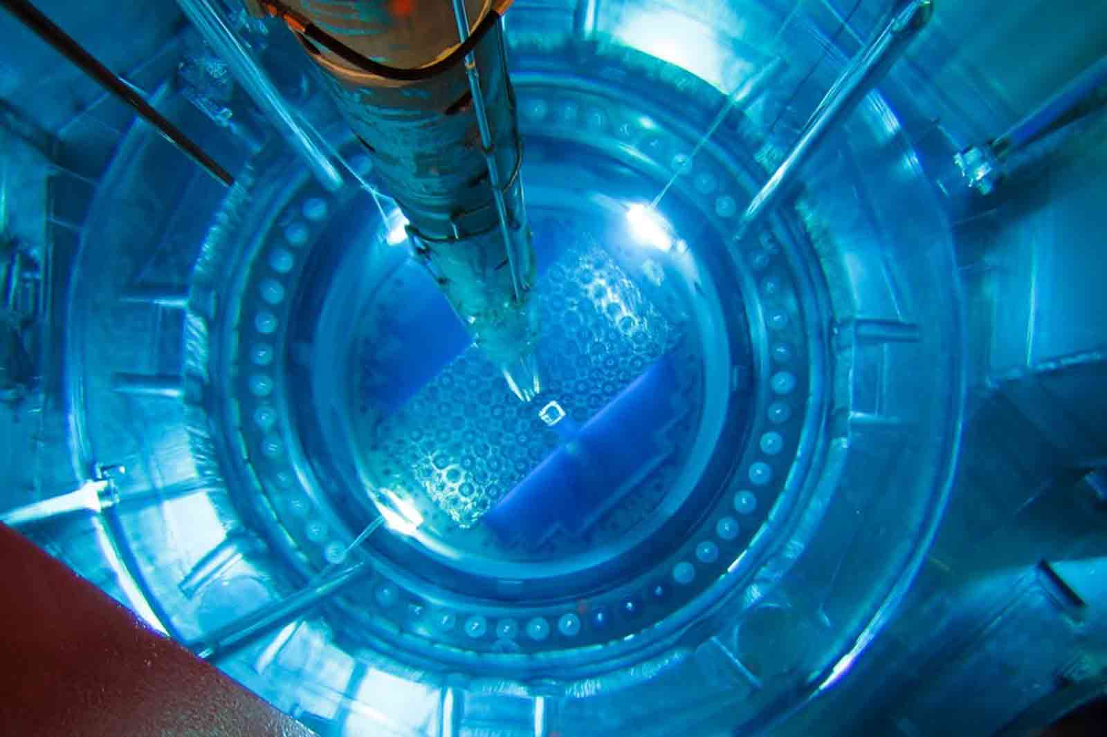 A top-down view of a nuclear reactor core with blue lighting, showcasing the fuel rods and hexagonal arrangements.