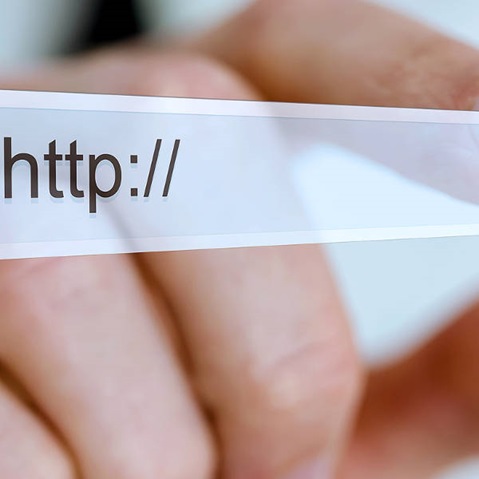 A hand holds a URL bar displaying 'http://' in focus, with a blurred background.