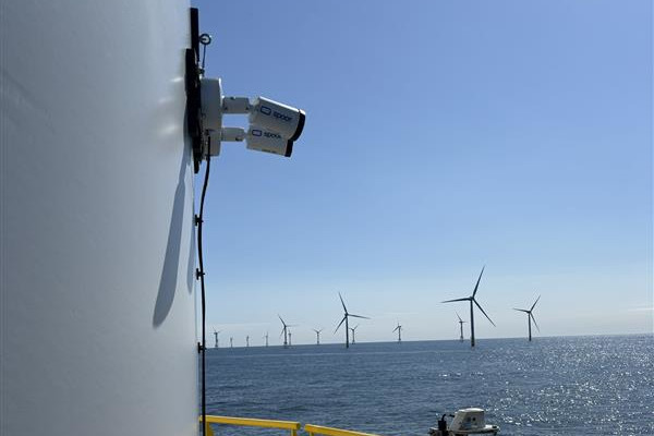 Auf dem Bild sieht man eine Offshore-Windfarm. Der Blick ist von einer Plattform auf dem Meer, mit Windturbinen im Hintergrund.