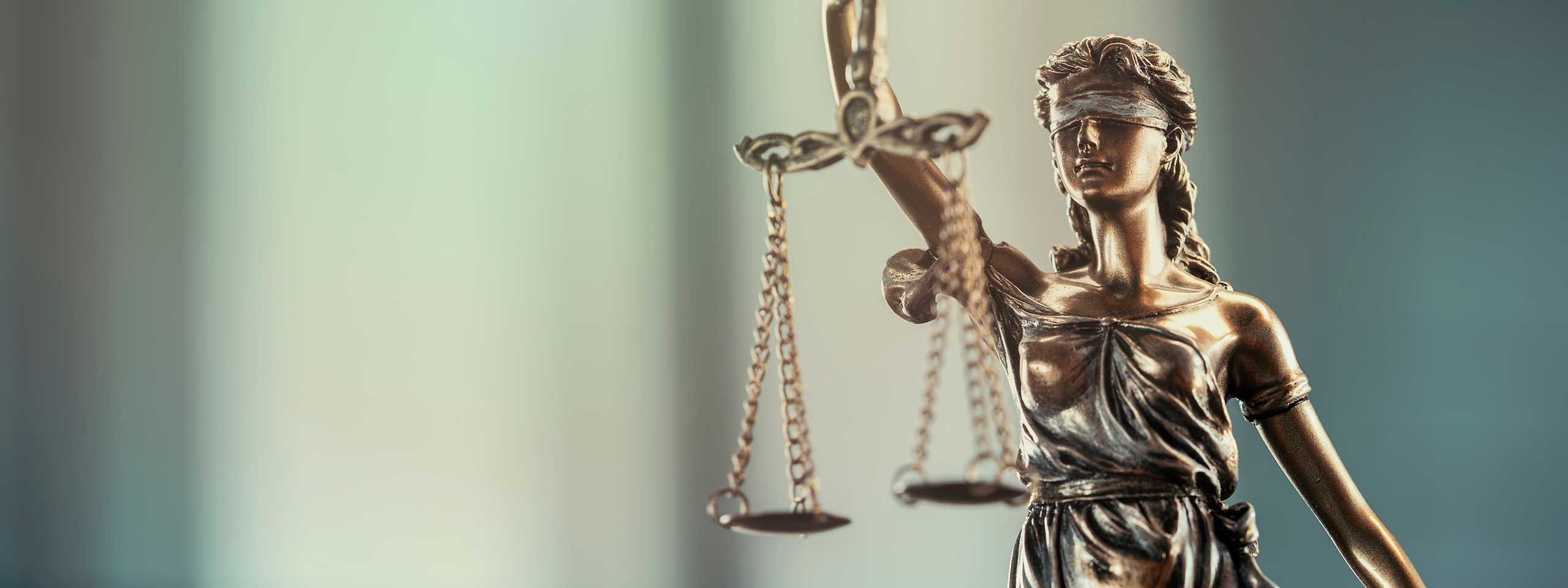 Eine Statue von Justitia hält eine Waage, symbolisiert Gerechtigkeit und Rechtsstaatlichkeit.