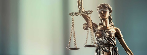 Eine Statue von Justitia hält eine Waage, symbolisiert Gerechtigkeit und Rechtsstaatlichkeit.