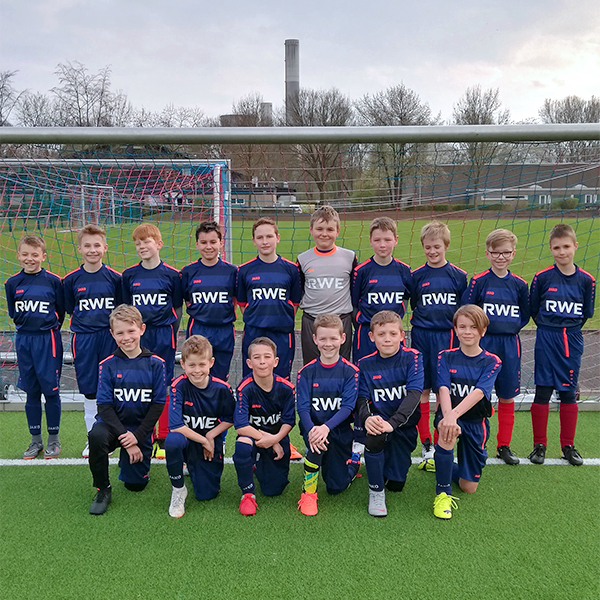 A football team poses on a pitch. All members wear matching kits featuring the RWE logo.