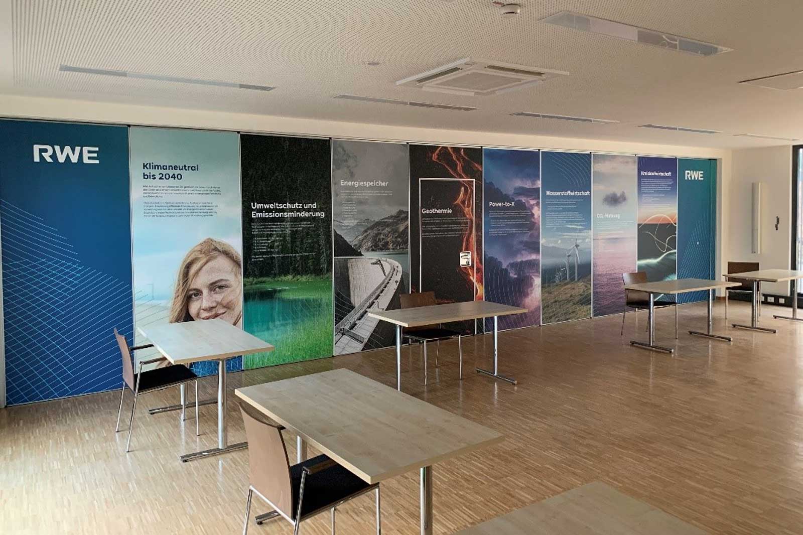 An office space with several tables, featuring informative posters on sustainability and energy solutions on the walls.