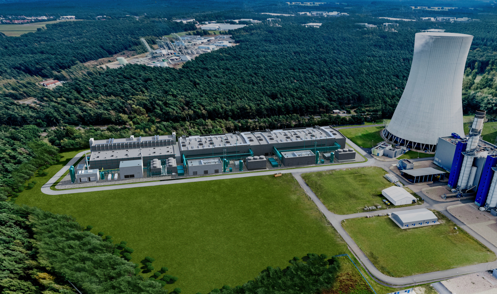 Aerial view of a large industrial facility surrounded by a forested area, featuring cooling towers and grey buildings.