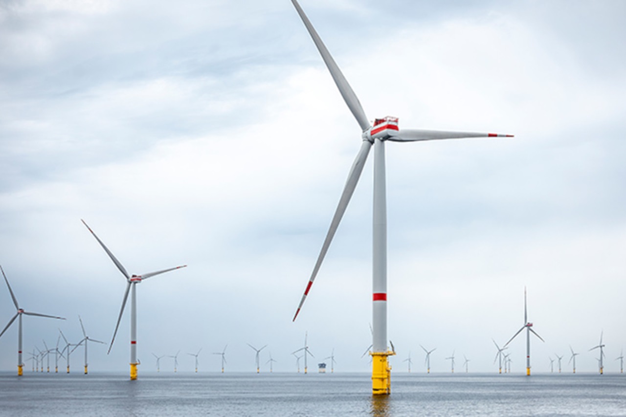 Offshore-Windkraftanlagen stehen bei bewölktem Himmel im Wasser. Einige Turbinen drehen sich im Wind.